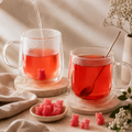 Bonbon à infuser Papothé rose dans une tasse en verre avec infusion fruitée rouge, accompagné de bonbons gourmands et d’une ambiance tea time douce et naturelle
